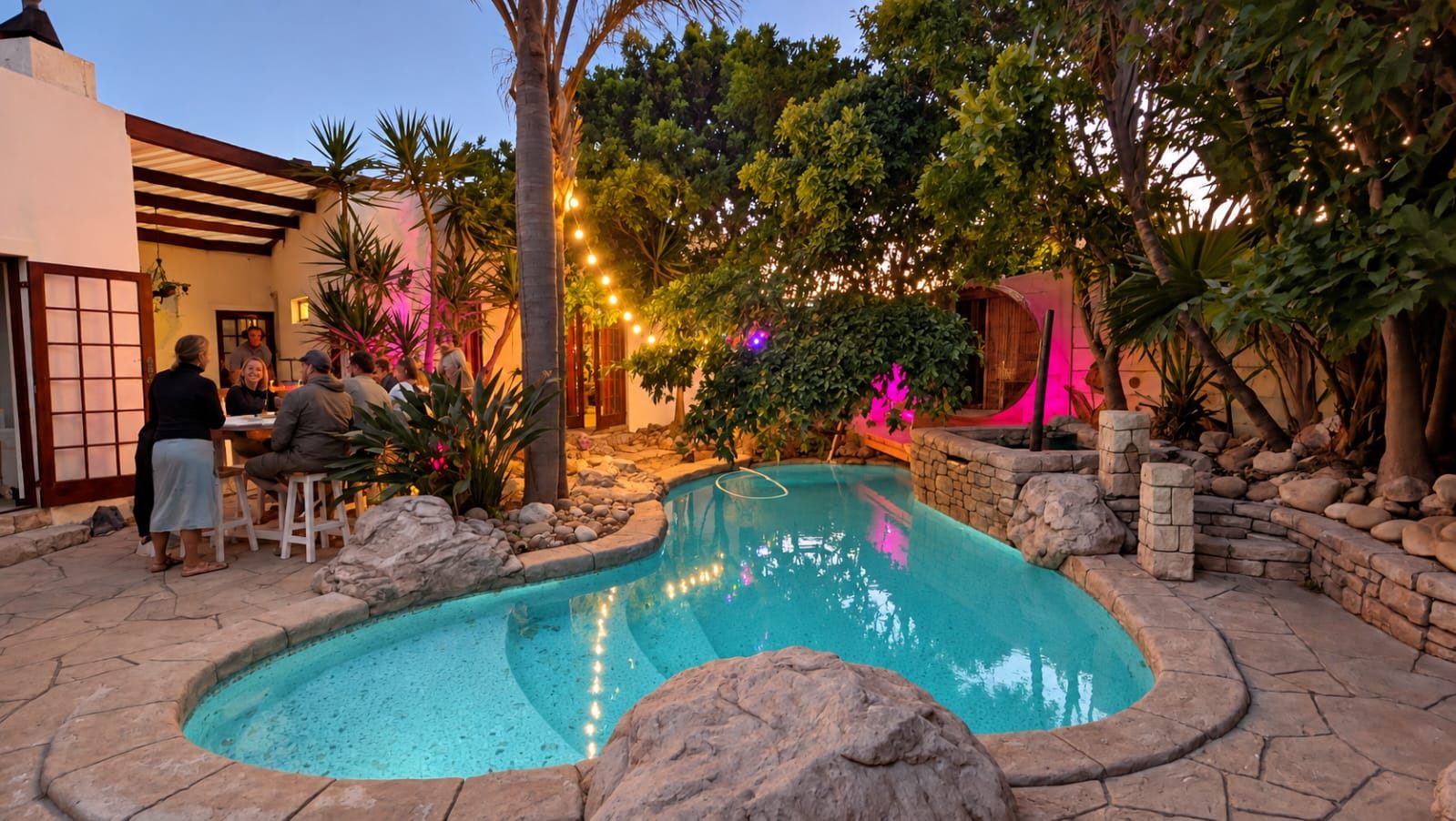 An evening at Khaya: the pool lit up and the Secret Sauna glowing in the garden
